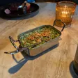 Creamed spinach topped with crisp pieces sits in a rectangular metal serving dish.