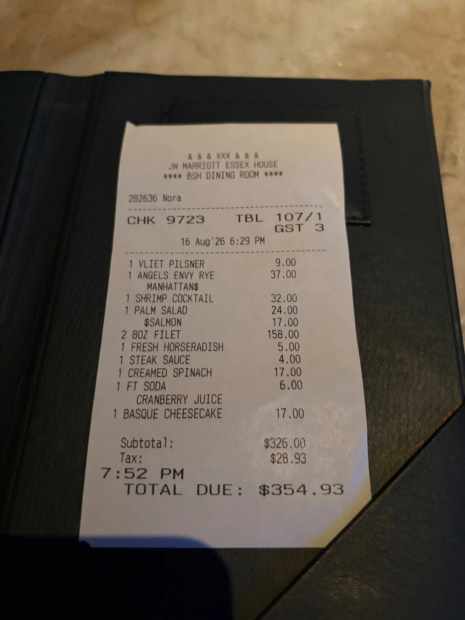 A printed dinner receipt lies in a black check presenter.